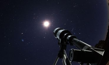 Telescópio de um planetário com visão do céu e das estrelas.