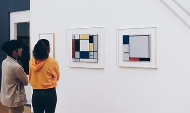 Pessoas observando obras em uma galeria de arte.