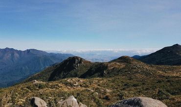 Morro com pedras e paisagem ao fundo.