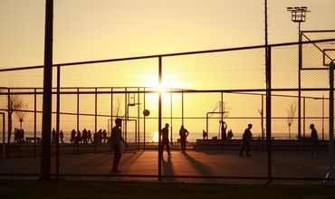 Pessoas praticando esportes em quadra de um centro esportivo.